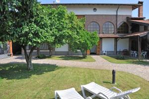 two white chairs sitting in the grass in front of a house at Bed & Breakfast Villa Chiara in Magenta