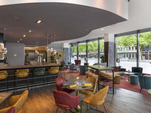 a restaurant with tables and chairs and a bar at Novotel Aachen City in Aachen