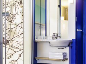 a bathroom with a sink and a mirror at ibis Budget Luxembourg Aeroport in Luxembourg +51 photos