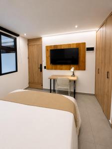 a bedroom with a bed and a table and a tv at Once Suites in Envigado