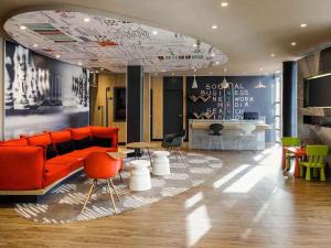 a living room with an orange couch and tables and chairs at Ibis Granada in Granada