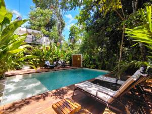 a swimming pool in a garden with chairs and trees at Yaakun in Bacalar