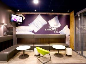 a waiting room with a couch and two tables and a tv at Ibis budget Berlin Potsdamer Platz in Berlin +70 photos