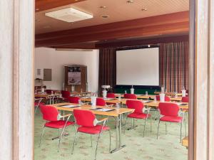 a classroom with tables and red chairs and a projection screen at Mercure Hotel Bad Duerkheim An Den Salinen in Bad Dürkheim +109 photos