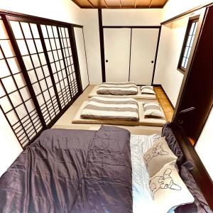 a room with three beds in it with windows at Between Kyoto & Osaka 渚西 駅徒歩6分 in Hirakata