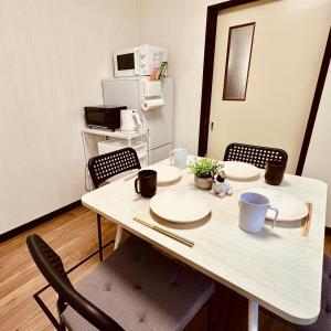 a dining room table with plates and chairs and a microwave at Between Kyoto & Osaka 渚西 駅徒歩6分 in Hirakata