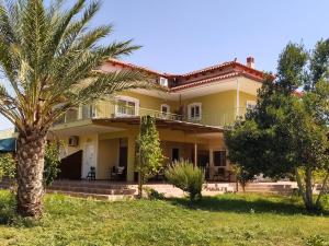a large yellow house with palm trees in the yard at Ktima Anastasia Olive Grove Nafplio in Nafplio