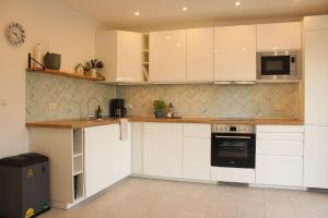 a kitchen with white cabinets and a microwave at Ferienwohnung "Groote Koje" in Barßel