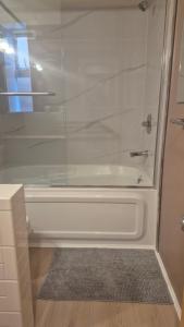 a bathroom with a shower and a white tub at Garden suite on Trinity St in Vancouver +11 photos