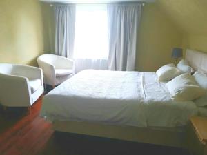 a bedroom with a bed and two chairs and a window at Charming Villa close to the sea in Errindlev