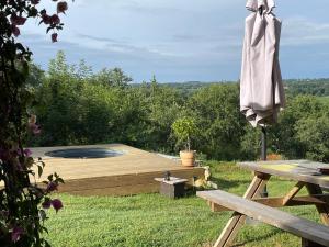 an umbrella sitting next to a wooden deck with a fire pit at Cabane Bivouac avec échelle à l'ombre des chênes in Idrac-Respailles