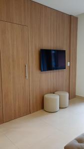 a living room with two stools and a flat screen tv at Apartamento Residence Ecoresort Capivari in Campina Grande do Sul