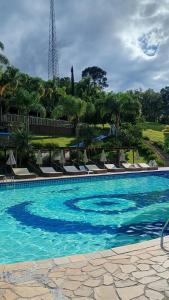 a large swimming pool with lounge chairs and trees at Apartamento Residence Ecoresort Capivari in Campina Grande do Sul