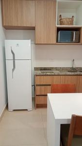 a kitchen with a white refrigerator and a microwave at Apartamento Residence Ecoresort Capivari in Campina Grande do Sul