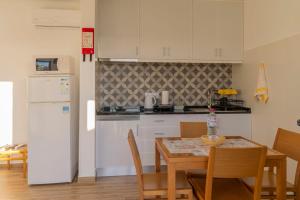 a kitchen with a table and a white refrigerator at Casa do Boto - Vagas D Alvorada in Santa Cruz