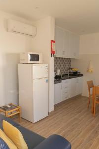 a small kitchen with a white refrigerator and a table at Casa do Boto - Vagas D Alvorada in Santa Cruz