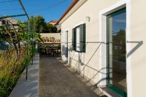 a white building with green windows and a sidewalk at Casa do Boto - Vagas D Alvorada in Santa Cruz