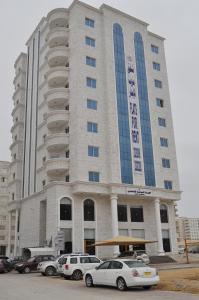 a large building with cars parked in front of it at Ganaen Salalah in Salalah