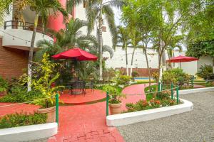a patio with a table and red umbrellas and plants at Hotel y Suites Los Encantos in Sayulita