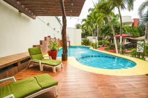 a swimming pool with a green couch and a chair at Hotel y Suites Los Encantos in Sayulita