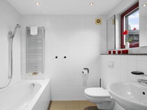 a white bathroom with a tub and a toilet and a sink at Seestrasse 35 in Insel Poel +15 photos