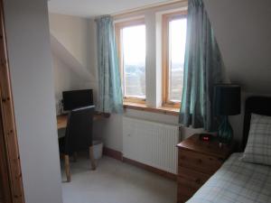 Un dormitorio con un escritorio y una cama y una ventana. en Seafar Bed & Breakfast, en Portree