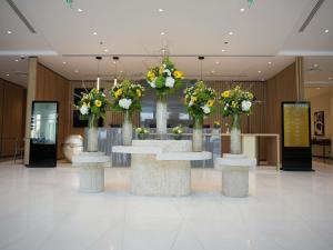 a lobby with three tables with flowers in them at Novotel Riyadh Al Anoud in Riyadh