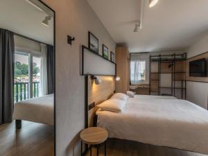 a hotel room with two beds and a balcony at ibis Ciboure Saint-Jean-de-Luz in Ciboure
