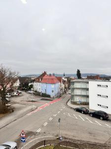 an empty city street with cars parked on the road at Modernes Apartment am Bodensee in Singen