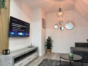 a living room with a couch and a tv on the wall at Modernes Apartment am Bodensee in Singen