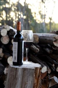 a bottle of wine and a glass on a stump at El Escondido Natural Glamp in Atos Pampa