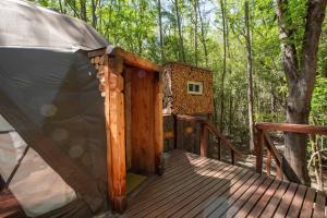 a tent on a wooden deck in the woods at El Escondido Natural Glamp in Atos Pampa +10 photos