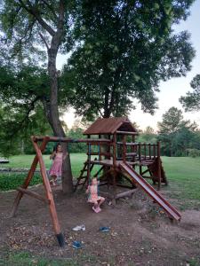 two children playing in a playground with a tree at El Escondido Natural Glamp in Atos Pampa