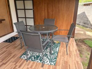 a glass table and four chairs on a patio at Fare Maeva in Paopao