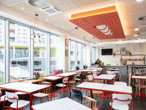 a dining room with tables and chairs and windows at ibis budget Leuven Centrum in Leuven