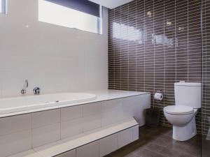 a bathroom with a toilet and a tub and a sink at Mercure Centro Port Macquarie in Port Macquarie
