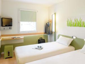 a hotel room with two beds and a tv at Ibis Budget Girona Costa Brava in Girona +36 photos