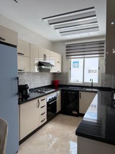 a kitchen with white cabinets and black appliances at Cozy appartement smir park in Tétouan