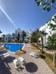 a resort with a pool and chairs and umbrellas at Cozy appartement smir park in Tétouan