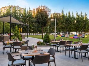 a restaurant with tables and chairs in a park at Novotel Kayseri in Kayseri