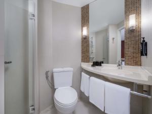 a white bathroom with a toilet and a sink at Ibis Bangkok Riverside in Bangkok