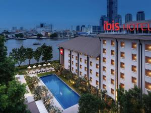 a hotel with a swimming pool in front of a building at Ibis Bangkok Riverside in Bangkok