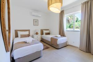 a bedroom with two beds and a window at Villa Ursa by Algarve Holidays in Praia do Carvoeiro +30 photos