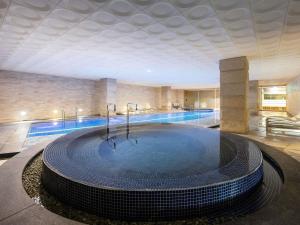 a large swimming pool in a building with a swimming pool at Grand Mercure Ambassador Changwon in Changwon