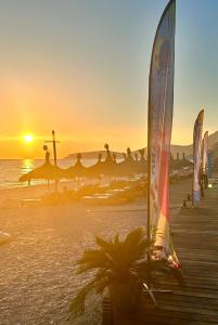 a sunset on a beach with umbrellas and the ocean at Borsh Grove Villa in Borsh
