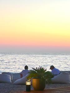 three people sitting on pillows on the beach at sunset at Borsh Grove Villa in Borsh +2 photos