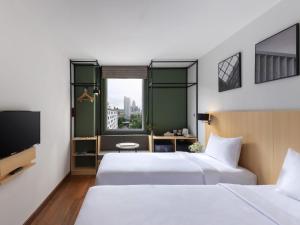 a hotel room with two beds and a television at Ibis Bangkok Sukhumvit 4 in Bangkok