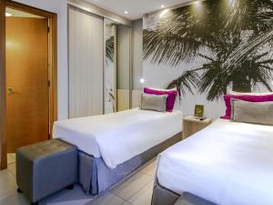 two beds in a hotel room with pink pillows at Mercure Salvador Boulevard Hotel in Salvador