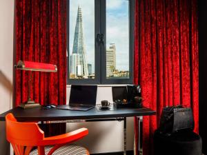 a desk with a laptop in a room with a window at ibis Styles London Southwark - near Borough Market in London