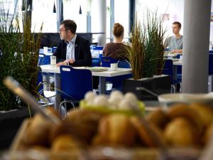a man in a suit sitting at a table in an office at Ibis budget Koeln Messe in Cologne
